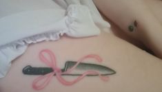 a woman's stomach with a knife and pink ribbon tattoo on her left side