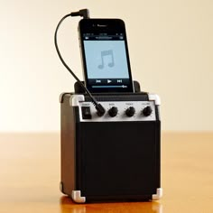 an ipod is plugged into a mini amp on a wooden table with ear buds