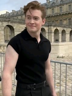 a man in black shirt standing next to a fence