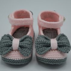 a pair of crocheted baby shoes with a bow on the front and bottom