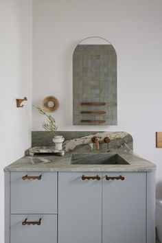 a bathroom sink sitting under a mirror next to a wall mounted faucet in a bathroom