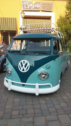 a blue and white vw bus parked in front of a building