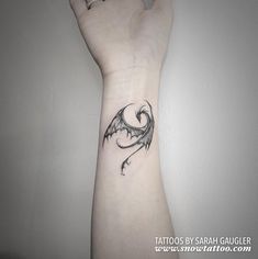 a black and white photo of a hand with a dragon tattoo on it's wrist