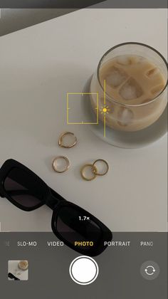 a pair of black sunglasses sitting on top of a table next to some gold rings