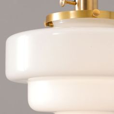 a close up of a light fixture on a gray background with white and gold accents