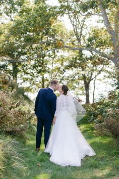 a bride and groom kissing in the woods