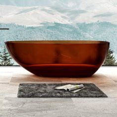 a bathtub sitting on top of a bathroom floor next to a window with mountains in the background