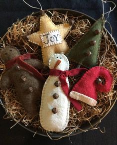 four christmas ornaments in a bowl with straw