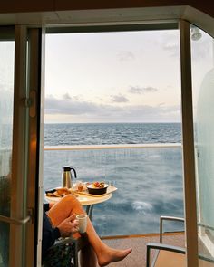 a woman sitting at a table on top of a boat looking out to the ocean