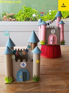 two paper castles sitting on top of a wooden table