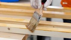 a person in white gloves painting wood with a brush