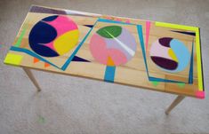 a table made out of wood with different colored shapes on it and a wooden stand