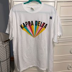 a white t - shirt with the words kapaa delia on it hanging from a rack