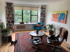 a living room filled with furniture and bookshelves in front of a large window