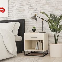 a bedroom with white brick walls, a bed and a nightstand next to a plant