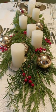 the table is set with candles and greenery for an elegant christmas centerpieces