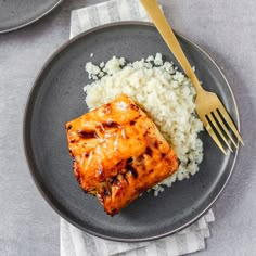 a plate with rice and chicken on it next to a fork, knife and spoon