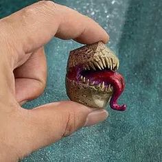 a hand is holding a toy that looks like a monster's mouth