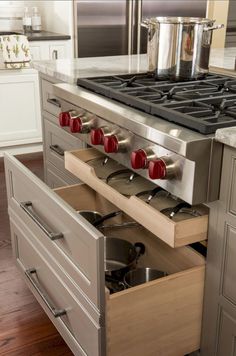 an open drawer with pots and pans on it in the middle of a kitchen