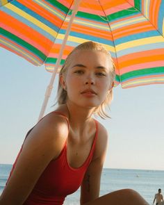 a woman sitting under an umbrella on the beach