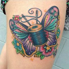 a woman's thigh with a tattoo on it and a spool of thread