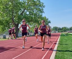 the girls are running down the track in their maroon shirts and black shorts, while one girl is on her cell phone