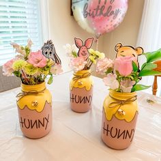 three vases with flowers in them sitting on a table next to a pink balloon