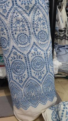 a blue and white pillow sitting on top of a floor next to a pile of clothes