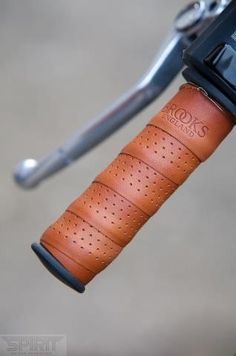 a close up of a bike handle with a leather case on the handlebars