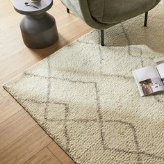 a living room with a chair and rug on the floor next to a coffee table