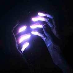 two hands holding something in the dark with light shining on it's palm and fingers