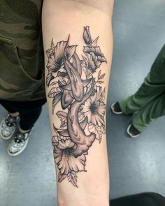 a tattoo on the arm of a woman with flowers and leaves around her wrist,