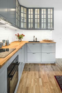 a kitchen with white cabinets and wood counter tops on a hardwood flooring area next to a stove top oven