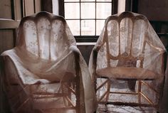 two chairs covered with white fabric in front of a window