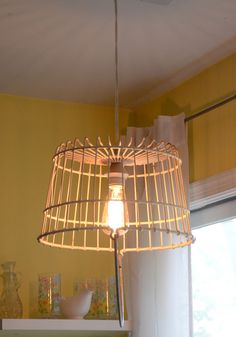 a cage light hanging from the ceiling in a room with yellow walls and white curtains