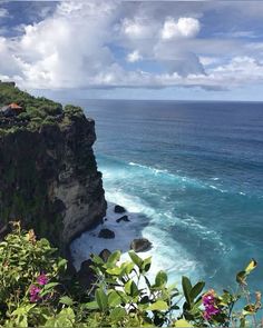 the ocean is blue and green with white clouds in the sky, along with cliffs on either side