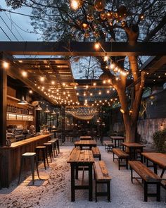 an outdoor restaurant with wooden benches and lights strung from the ceiling over it's tables