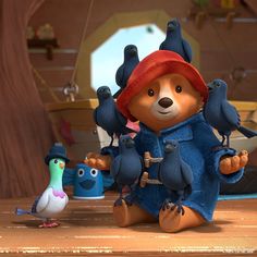 a teddy bear and some birds on a wooden table in the animated version of paddington