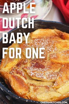 an apple dutch baby for one in a cast iron skillet with powdered sugar on top