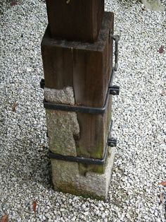 a wooden post with metal bars attached to it on top of some rocks and gravel