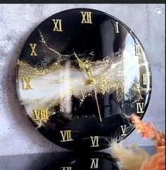 a black clock with roman numerals on the face and gold numbers is shown