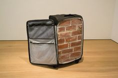 a piece of luggage sitting on top of a wooden floor next to a brick wall