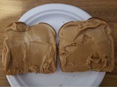 two pieces of toast with peanut butter on them sitting on a plate next to each other