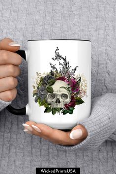 a woman holding a coffee mug with a skull and flowers on it