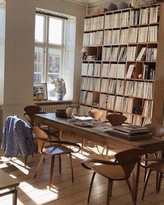 a dining room table and chairs in front of a bookshelf filled with records