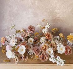 a bunch of flowers sitting on top of a wooden table in front of a wall