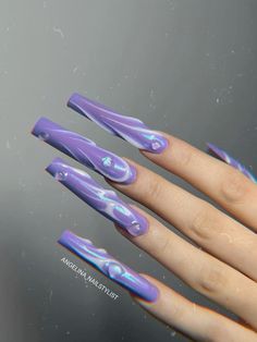 a woman's hand with purple and blue nail designs on it, holding onto a mirror