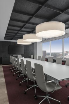 an empty conference room with white tables and chairs in front of large windows overlooking the city