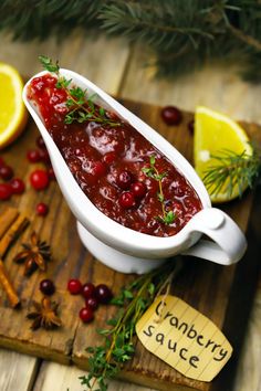 cranberry sauce in a serving dish on a cutting board with lemons and spices