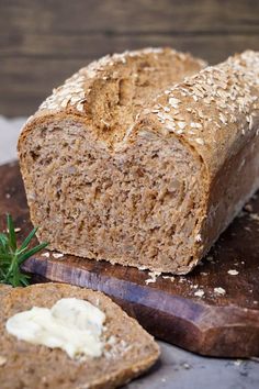 a loaf of bread sitting on top of a cutting board next to a piece of bread